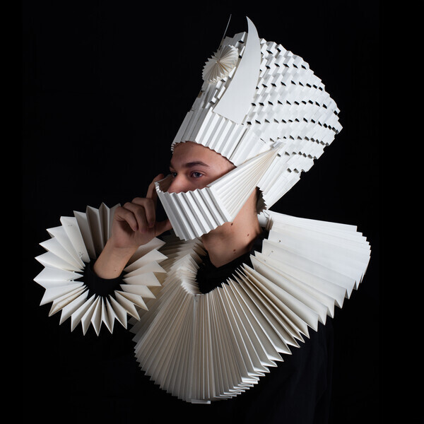 Portrait einer Person die eine 3D Körperhülle aus Papier trägt.