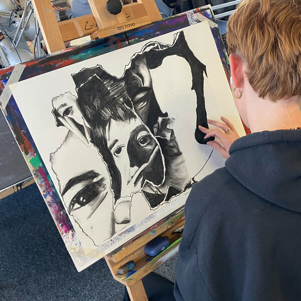 Person zeichnet Portrait mit Kohle im Unterricht an einer Staffelei